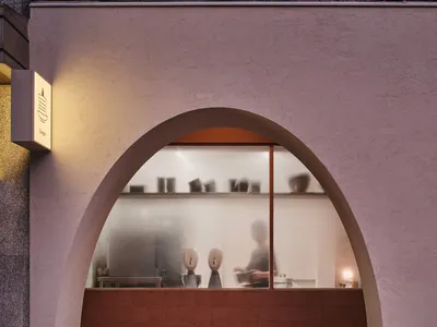 A welcoming storefront with a curved glass window showcasing bowls in various positions, with two people present in the scene
