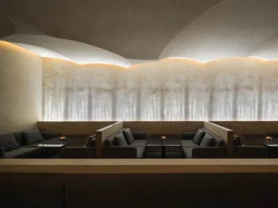 Empty modern restaurant with grey walls, tables, and chairs, creating a calm and inviting atmosphere