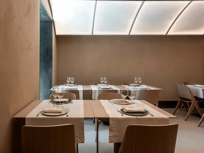 餐廳用餐區配有白色桌布、酒杯與舒適座椅，營造出乾淨清爽且溫馨邀請的氛圍