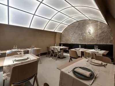 空蕩蕩的餐廳，配有木桌椅、石牆與酒杯，顯示營業中狀態