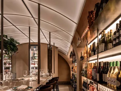 A warm and inviting dining space with wine bottles and glasses, tables, and chairs, perfect for socializing and fine wines