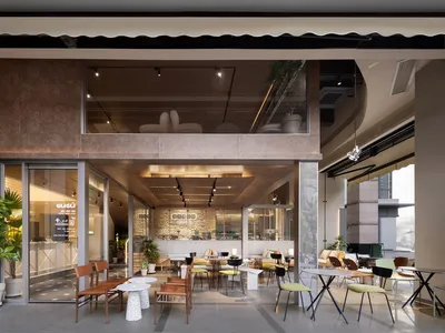 A well-lit restaurant interior with tables, chairs, potted plants, and decorative elements, creating a warm and inviting atmosphere