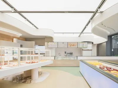 A modern restaurant kitchen and dining area with a large counter, dining table, and comfortable seating for guests