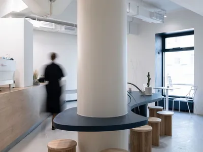 Modern restaurant interior with a central pillar, dining tables, and chairs, giving off a stylish and modern vibe