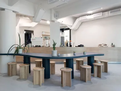 溫暖舒適的開放式廚房區域，配有大型餐桌、盆栽植物和咖啡機，周圍環繞舒適座椅與自然光線