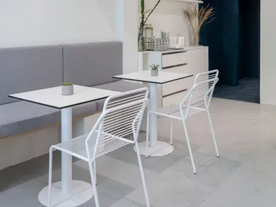 A restaurant interior with white walls, wooden tables, and decorative elements such as potted plants, vases, and bottles