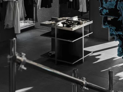 A modern retail space with a black and white color scheme, featuring dresses and handbags on display, with warm and inviting lighting