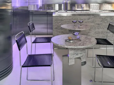 Modern restaurant interior with purple neon lights, sleek surfaces, dining area, kitchen, and contemporary design