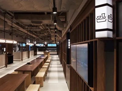 A modern restaurant with a large dining area featuring multiple tables and chairs, and benches, well-lit for a welcoming atmosphere