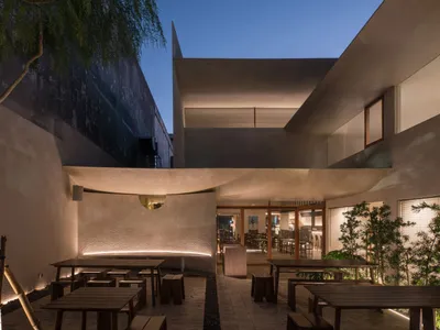 A modern restaurant interior with concrete walls, dining tables, and chairs, creating a stylish and inviting atmosphere