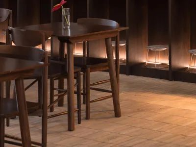 A restaurant interior with wooden floors and walls, featuring multiple dining tables, chairs, and wine glasses, creating a warm and inviting atmosphere