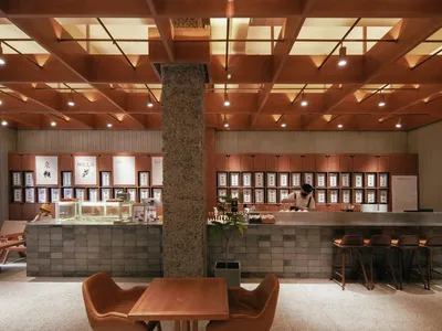 A casual restaurant dining area with wooden tables, chairs, and multiple people enjoying their meals
