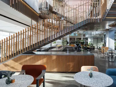 Open dining space with wood flooring, multiple tables, chairs, and potted plants, creating a modern and inviting atmosphere