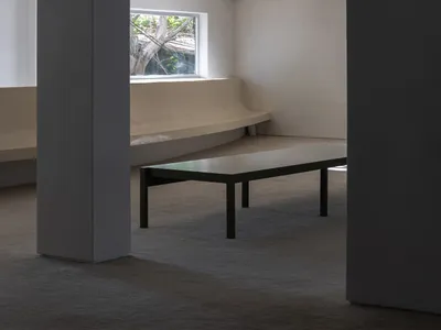 Empty living area with a bench in front of a large window, allowing sunlight to enter