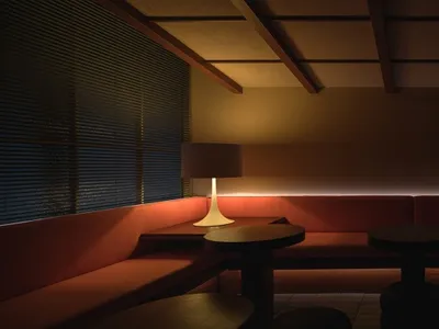 Inviting restaurant interior with a long bench seating area, multiple tables, chairs, and a couch, creating a cozy atmosphere for dining and socializing