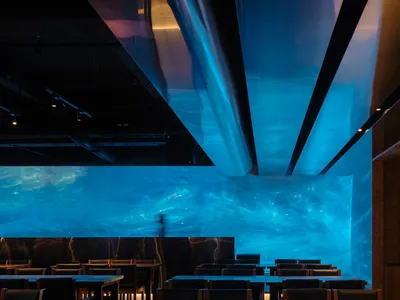 A modern restaurant interior with a large blue ocean mural, comfortable seating, and a sophisticated atmosphere