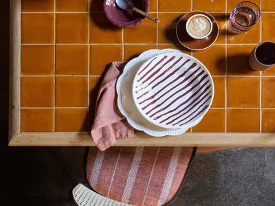 A kitchen dining area with a wooden table set up with food, cups, and apples, creating a warm and inviting atmosphere