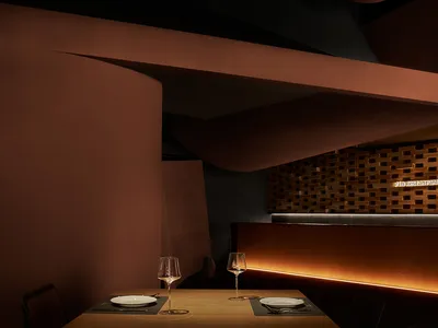 Dining area with wooden furniture, brick walls, and wine glasses, conveying a warm and inviting atmosphere