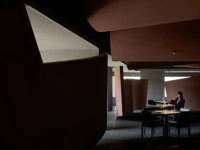 紅牆溫馨客廳與餐廳空間，配有沙發、椅子、餐桌與筆電，營造溫暖舒適的氛圍