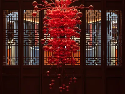 A dimly lit room with an ornate red chandelier and dark background, creating a sophisticated atmosphere