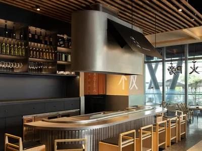 Modern Asian restaurant bar with a countertop, chairs, and bottles of various sizes displayed, creating a functional and stylish atmosphere