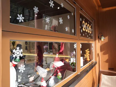 A retail storefront window display of winter clothing items with snowflakes on the glass, set against a background of people in a retail environment