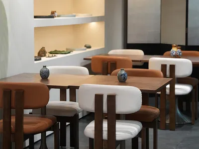Modern restaurant interior with wooden tables and chairs, white walls, and brown wood accents, creating a warm and inviting atmosphere