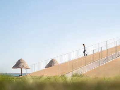 A man walks up a concrete staircase with a metal railing, surrounded by natural light and a casual atmosphere