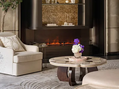 Cozy living room with a fireplace, two couches, a chair, and a potted plant, with warm lighting and a sense of evening atmosphere