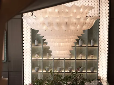 Elegant interior design showroom with a large chandelier, vases, books, and high-end materials