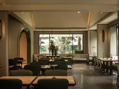 Modern restaurant interior with tables, chairs, potted plants, and inviting ambiance