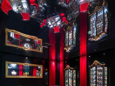 Elegant restaurant interior with red walls, black tables and chairs, and artwork on the walls