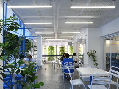 casual dining space with wooden tables and chairs, people sitting and standing around, well-lit