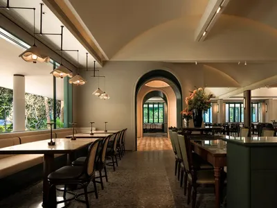 An inviting restaurant interior with a large dining table, multiple chairs, and several potted plants