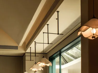 Empty restaurant interior with natural light, dining tables, chairs, and hanging lights