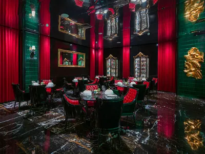 Ornate dining area with a large table, black leather chairs, and wine glasses, set in an elegant and sophisticated atmosphere