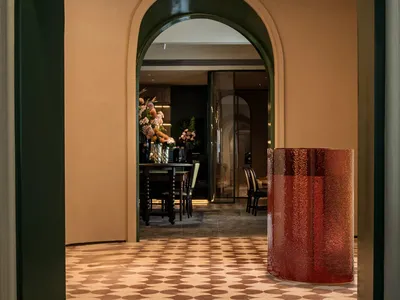 Dining area with a table and chairs surrounded by potted plants, a vase, and a doorway to other rooms, exuding luxury and refinement