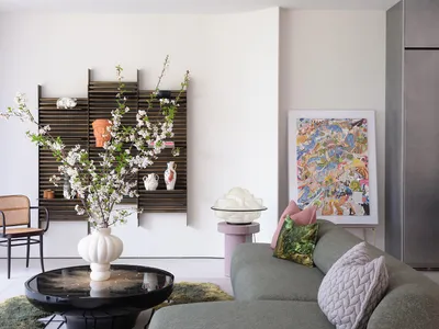 Cozy open living area with a couch, chair, dining table, potted plants, and decorative vases