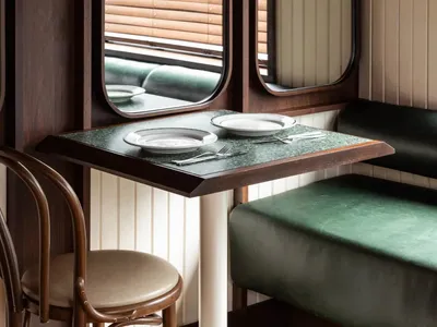 A dining area in a restaurant with a wooden table surrounded by chairs, set with plates, cutlery, and bowls, creating a warm and inviting atmosphere