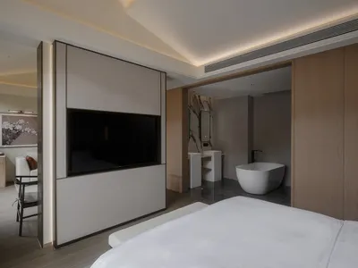 Modern bathroom with a white bathtub, flat screen TV, and neutral-toned walls, creating a clean and airy atmosphere