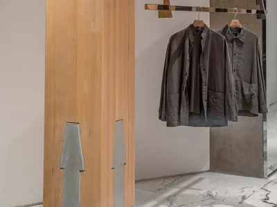 A store display featuring hanging clothes on a wooden rack, creating a sense of organization and cleanliness in a retail environment
