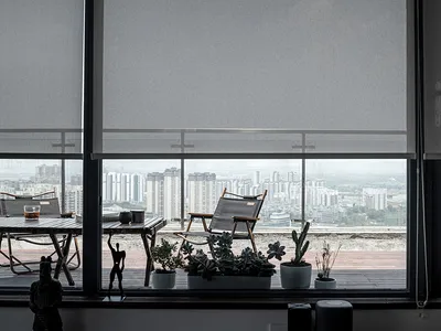 Cozy indoor living area with a large window offering a city view, potted plants, and a chair for seating
