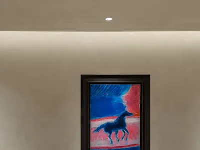 Cozy living room with a large picture frame, TV, speakers, and a clock, featuring a painting of a horse and a warm atmosphere