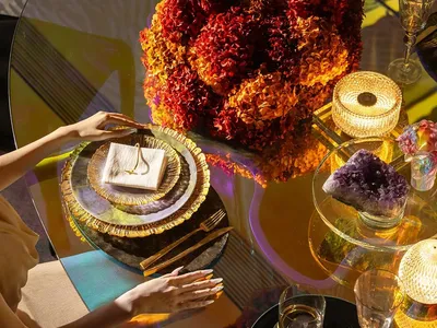 餐桌擺設紅色花卉中心桌花、紅酒杯、書籍與精緻瓷器，位於奢華餐廳環境