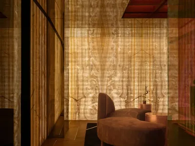 Cozy living area with a couch and two chairs, dimly lit with wood and stone wall features