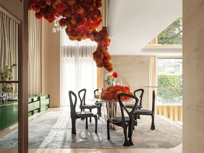 Inviting open concept living area with a dining table, couch, and decorative elements such as potted plants, vases, and flowers