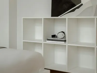 A calm and inviting bedroom with a large bookshelf filled with books, a clock, and a focus on organization and relaxation