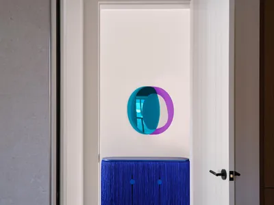 Cozy living room with a blue couch in front of a mirror with a purple circle design, two chairs, and a doorway leading to another room