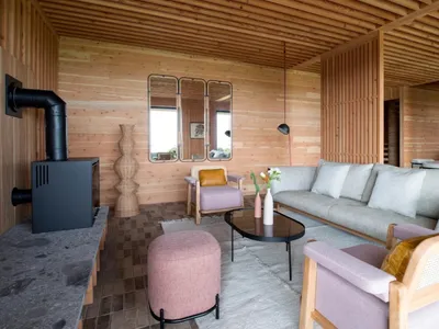 Warm and inviting living area with a large couch, fireplace, wooden floors, and a dining table in the background