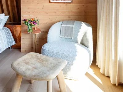 Warm and cozy living space with wooden walls and floors, featuring two chairs and a decorative vase on a table